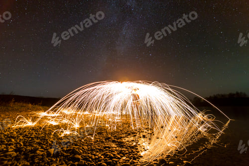 Preview: Light painting art concept. Spinning steel wool in abstract circle, firework showers of bright