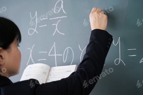 Preview: A Japanese woman teacher writes on the blackboard in her classroom