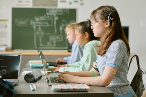 Preview: Teenage Girls and Boy Collaborating on Laptops in Classroom Setting