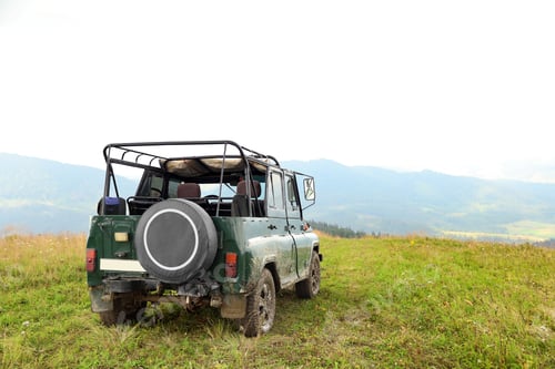Preview: Dirty car on green hill in wilderness