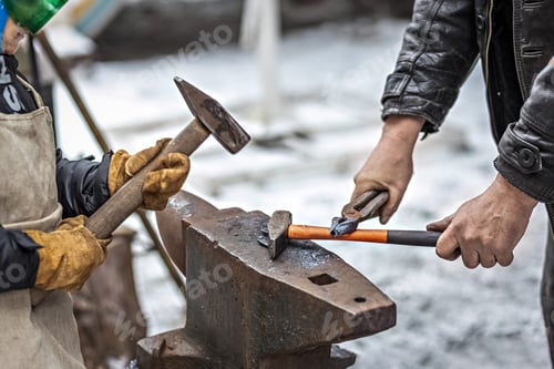 Preview: A blacksmith man and his son forge a horseshoe on an anvil