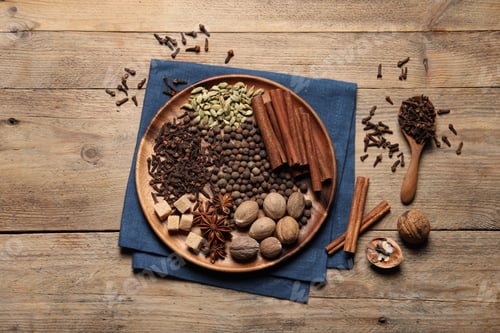 Preview: Spoon with different spices and nuts on wooden table, flat lay