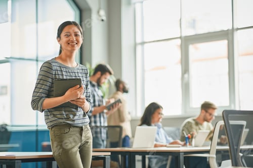 Preview: Amicable young woman looking accomplished at her workplace