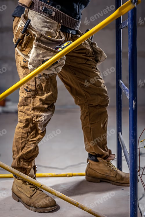 Preview: A male electrician works in a switchboard with an electrical connecting cable.