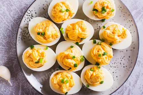 Preview: Closeup of eggs filled with a mixture of yolk, cheese, garlic and mayonnaise on a plate top view