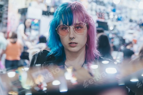 Preview: Beautiful young female with sunglasses and a leather jacket in front of illuminated amusement park