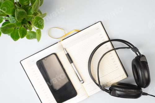 Preview: Headphones, a notebook, a mobile phone and a houseplant on an indoor table, flat lay