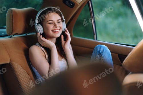 Preview: Young woman enjoying music in car with headphones, smiling happily in a casual outfit, surrounded by