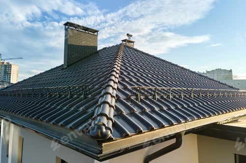 Preview: Closeup snow guard for safety in winter on house roof top covered with ceramic shingles. Tiled