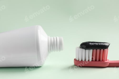 Preview: Brush and tube with charcoal toothpaste on white background, closeup