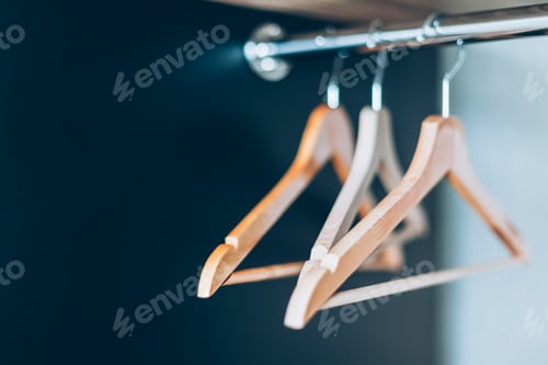Preview: Wooden clothes hangers hanging in dark empty closet