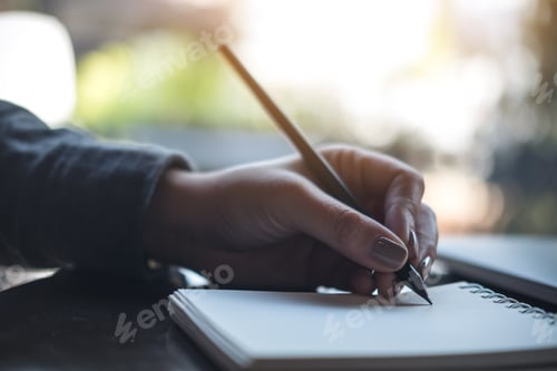 Preview: Closeup image of a woman's hands writing on notebook on the table