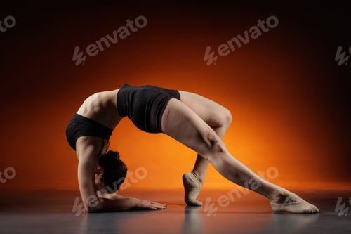 Preview: Flexible woman in forearm backbend stretch in studio with orange copy space