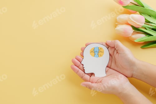 Preview: Hands holding brain jigsaw in head paper cut symbolizes Down Syndrome Day.
