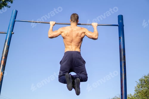 Preview: Muscular Caucasian man workout pull ups at outdoor
