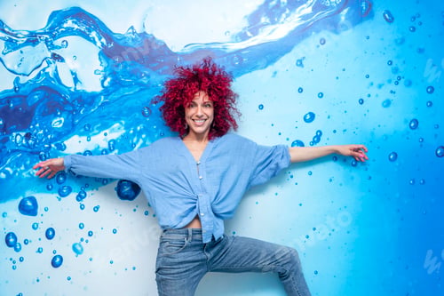 Preview: portrait of a smiling young latin woman with afro hair posing on a blue background with blue drops