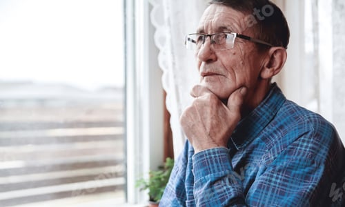 Preview: Senior standing at the window and thinking about something or fo