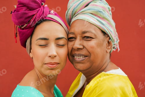 Preview: African mother and daughter having tender moment together while wearing traditional dress