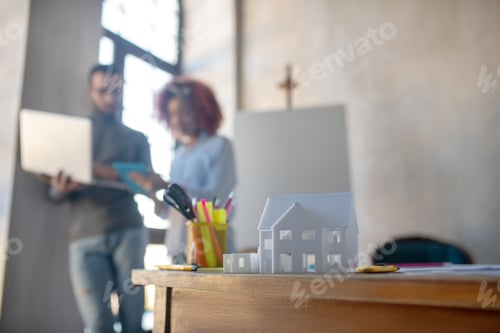Preview: House model standing on table near interior designers