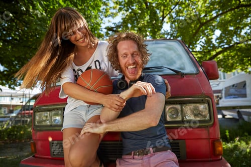 Preview: Young couple fooling around outdoors, laughing, young woman holding basketball
