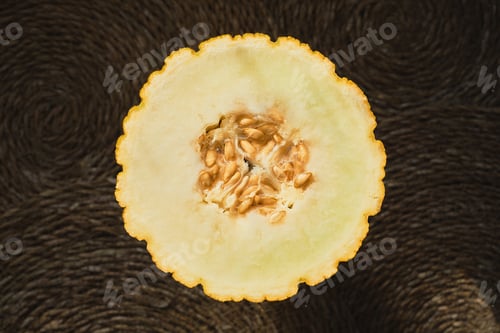 Preview: Juicy melon cut in half on a straw deck, top view, organic fruit