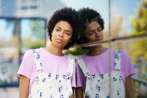 Preview: Thoughtful upset African American woman lost in thoughts outdoors.