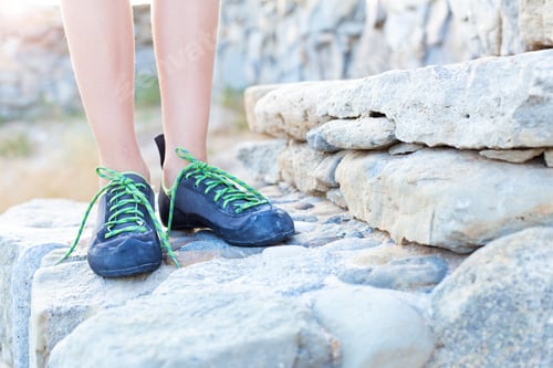Preview: Legs in climbing shoes, standing on the stone steps, close-up.