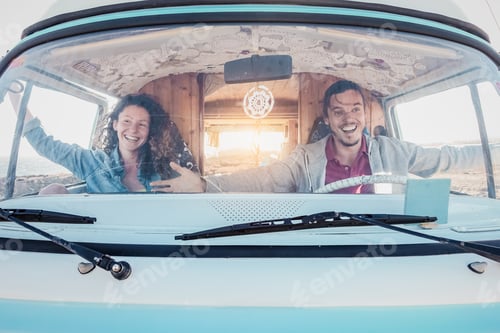 Preview: Happy travel couple having fun driving vintage minivan during road trip tour