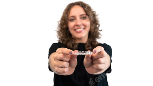 Preview: Female hand holding dental aligner retainer of dental clinic for teeth treatment