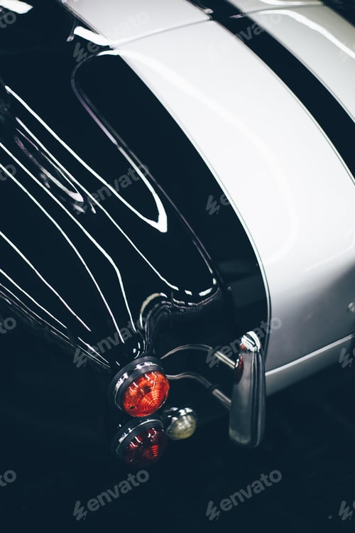 Preview: Vertical selective closeup shot of the taillight of a black and white car