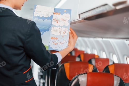 Preview: Holds paper with instrucitons. Young stewardess on the work in the passanger airplane