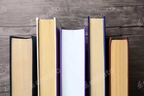 Preview: Collection of different books near wooden wall, closeup