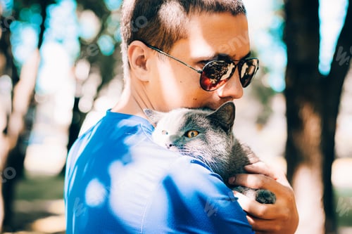 Preview: A man with a cat in his hands on the street lifestyle