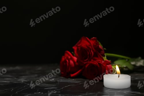 Preview: Beautiful red roses and candle on table against black background. Funeral symbol