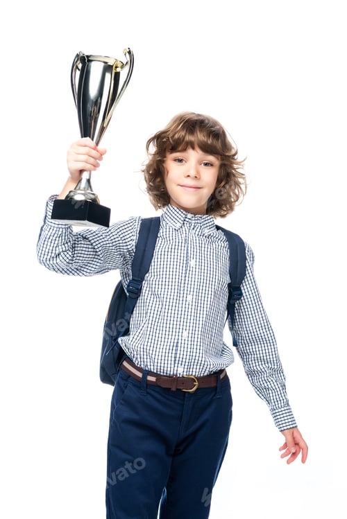 Preview: cheerful schoolboy with backpack holding winner cup isolated on white and looking at camera