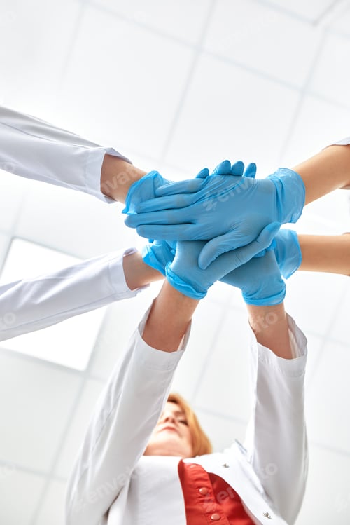 Preview: Hands in blue gloves covid, concept - creative team with hands on top of each other. Diverse team