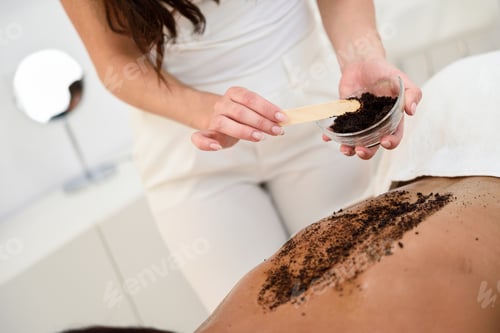 Preview: Woman cleans skin of the body with coffee scrub in spa wellness