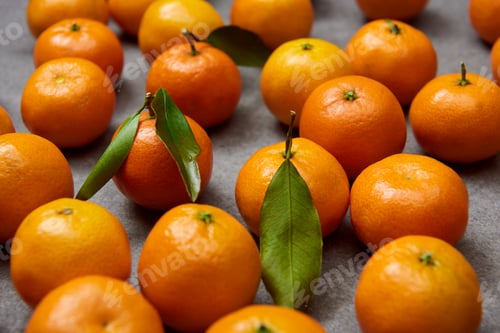 Preview: selective focus of orange tangerines with green leaves on grey table
