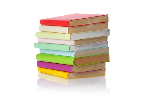 Preview: Colorful stack of books placed on a white table in a simple setting during the day
