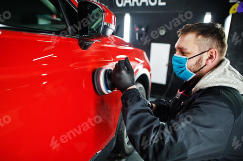 Man Polishing a Red Car in a Garage