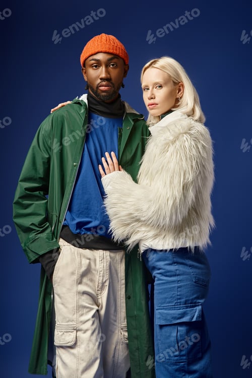 Preview: blonde woman embracing african american man in winter attire of blue backdrop, diverse couple