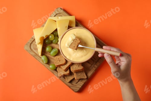 Preview: Concept of delicious food with fondue on orange background