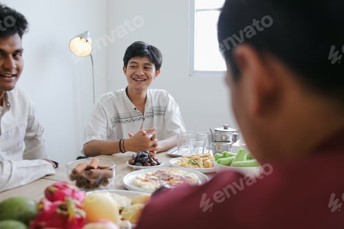 Preview: Happy Asian Muslim Friends Having Iftar Dinner Together on Ramadan Feast at Dining Table