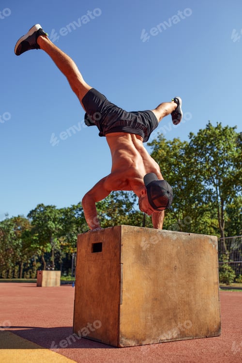 Preview: Sporty physically fit man doing step-up exercise on wooden box while doing gym training in sports