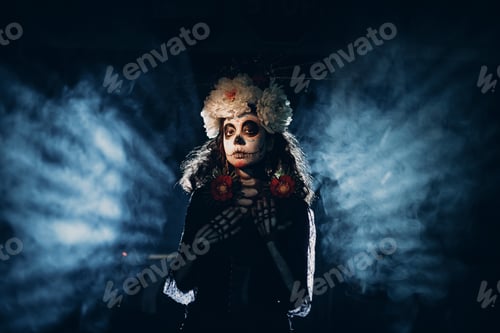 Preview: Woman with mexican skull halloween makeup in dark with backlight rays.