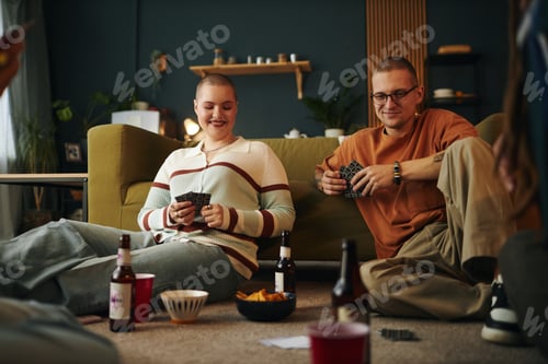 Preview: Young Friends Enjoying Card Game on Cozy Living Room Floor