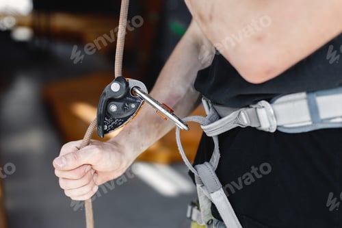 Preview: Cropped photo of safety harnesses in man's hand in climbing center