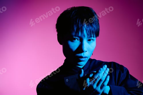 Preview: Stylish young man poses dramatically against a vibrant pink and blue backdrop
