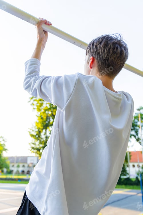Preview: Young Boy Doing Pull-Ups on a Horizontal Bar Outdoors