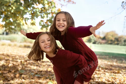 Preview: Caucasian child siblings having fun in the woods while playing piggyback